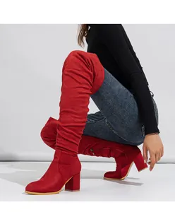 Close-up of red suede over-the-knee boots with chunky high heels worn by a model