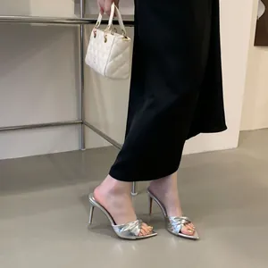 Silberne Mules mit Stiletto-Absatz und elegantem Knotendetail am Fuß des Models
