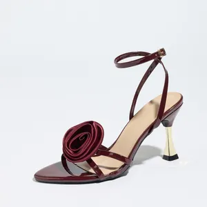 Elegant burgundy sandals with oversized rose detail and gold stiletto heel for women.