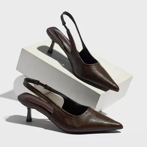Detail shot of brown pointed-toe slingback heels on white geometric blocks.