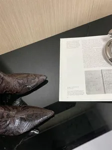 Detailed view of pointed toe and snake pattern texture on high heel boots