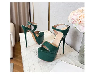 Dark emerald green patent leather platform stilettos with ankle strap detail on table