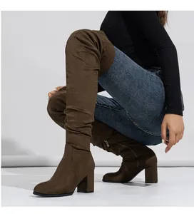 Detailed macro view of stylish brown suede over-the-knee boots with chunky heels