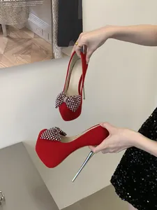 Detail von eleganten roten Wildleder-High-Heels mit Strass-Schleife und Plateau