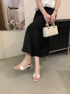 Close-up view of elegant white high heel mules featuring a rhinestone buckle and square toe