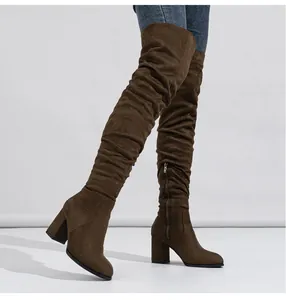 Close-up of fashionable brown suede over-the-knee boots featuring chunky high heels