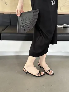 Sandales à talons bobines et fines lanières noires portées dans un décor minimaliste.