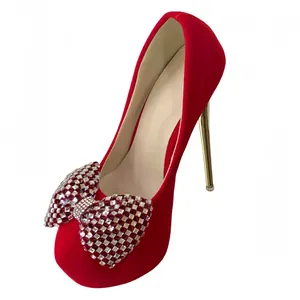 Detail of red stiletto platform pumps featuring a sparkling rhinestone bow on the toe