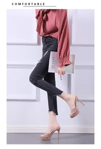 Elegant side view of nude platform peep-toe high heel mules worn with distressed denim jeans