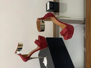 Detail view of burgundy suede platform sandals with gold metallic heels and ankle straps.