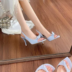 Elegant light blue French style sandals featuring bow detail and slim high heels on wooden floor
