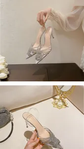 Dettaglio di sandali argento con strass, cinturini incrociati e cinturino in PVC.