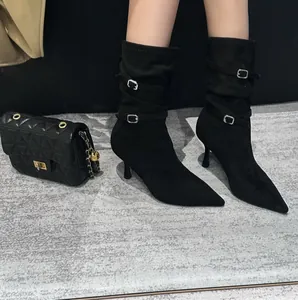 Macro detail view of black pointed-toe slouchy stiletto boots featuring buckle straps.