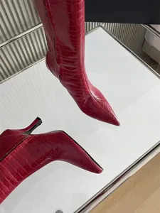 Detailed view of red crocodile-embossed leather pointed toe stiletto high heel boots