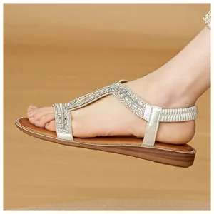 Vista laterale di sandali boho argento con cinturino a T in strass luccicanti.