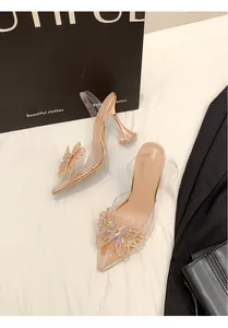 Detailansicht von transparenten PVC-Pumps mit funkelnder Strass-Schleife und Absatz
