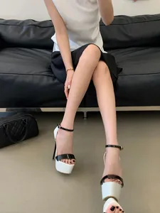 Close-up view of 16cm high heels with white platform and black ankle strap on model
