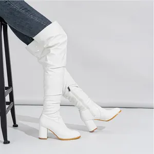 Detailed view of white patent leather slouchy over-the-knee boots with chunky heels