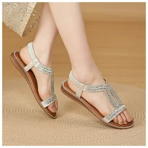 Vista dettagliata di sandali piatti boho con strass scintillanti e cinturini elastici.