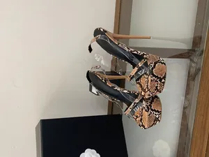 Detailed side view of high platform stiletto sandals featuring snake print and clear straps