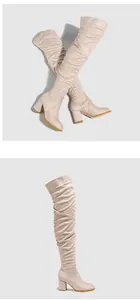 Detailed view of fashionable beige suede over-the-knee boots with chunky high heels.