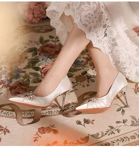 Elegant white pointed-toe stiletto heels featuring a luxurious sparkling rhinestone buckle
