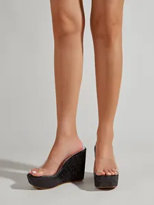 Detailweergave van modieuze sleehaksandalen met glitterplateau en transparant riempje