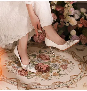 Elegant white bridal pumps with pointed toe and sparkling rhinestone flower embellishments