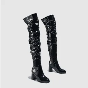 Sleek black patent leather over-the-knee slouchy boots with chunky block heels.