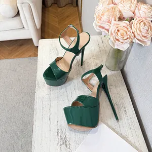 Close-up of green patent leather platform sandals with stiletto heels on white wood