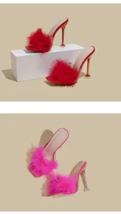 Detailed view of fashionable high-heeled slippers with red and pink feathers and transparent heels.