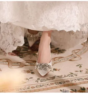 Close-up of white satin pointed-toe bridal pump with sparkling crystal flower buckle