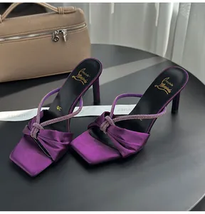 Close-up of purple satin high heel sandals with rhinestone straps and knot detail.