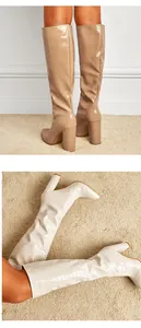 Detail view of crocodile-patterned pointed toe knee-high boots with block heel