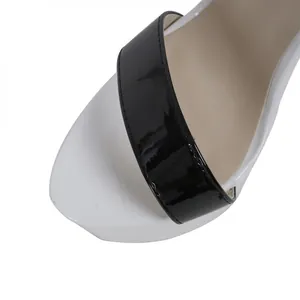 Close-up detail of the black patent leather strap on a stylish white platform sandal