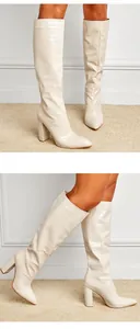 Detailed view of cream crocodile-embossed pointed toe block heel knee-high boots