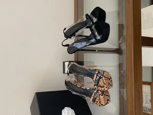 Detail view of platform high heel sandals in black suede and snakeskin with clear straps