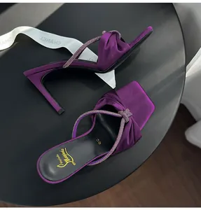 Close-up of purple satin high-heel sandals with a sparkling rhinestone knot strap