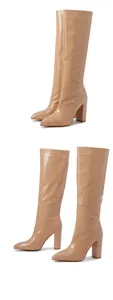 Detail view of beige croc-embossed knee-high boots with pointed toe and chunky heels