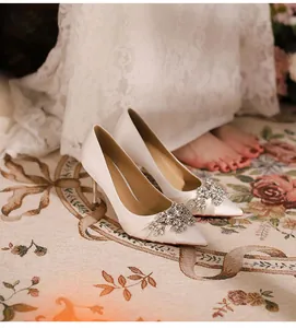 Detail shot of elegant white pointed-toe stiletto heels with crystal rhinestone buckles