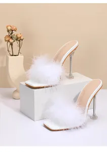 Close-up showing the soft white faux fur detail and sleek clear stiletto heels of these mules