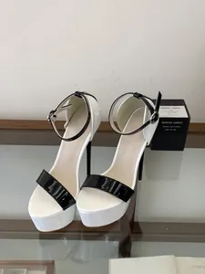 Close-up of elegant white and black patent leather 16cm platform sandals with ankle strap