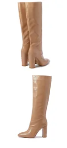 Detail of beige crocodile pattern knee-high boots with pointed toe and chunky high heel.
