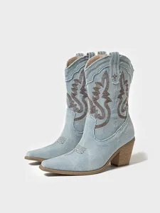 Detailed view of light blue denim western boots with brown embroidery and chunky heel