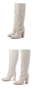 Close-up of cream crocodile textured knee-high boots with pointed toe and block high heel