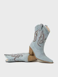 Detailed macro shot of light blue denim western cowboy boots with brown embroidery