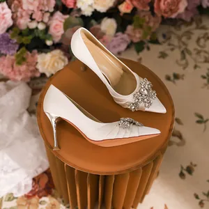 Elegant white pointed-toe high heels with sparkling rhinestone brooches and stiletto heels