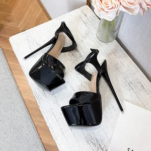 Detailed view of black patent leather platform sandals with extreme stiletto heels.