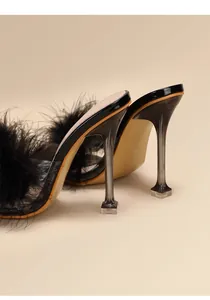 Detailed shot of black feather high heel mules featuring transparent stiletto heels