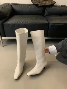 Detailopname van retro gebroken witte kniehoge rijlaarzen met een comfortabele lage hak
